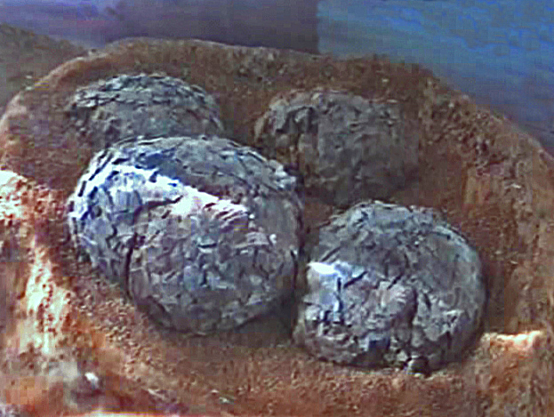 Four cracked dinosaur eggs nestle in a sandy, brown nest under soft lighting, evoking a sense of ancient life and mystery.