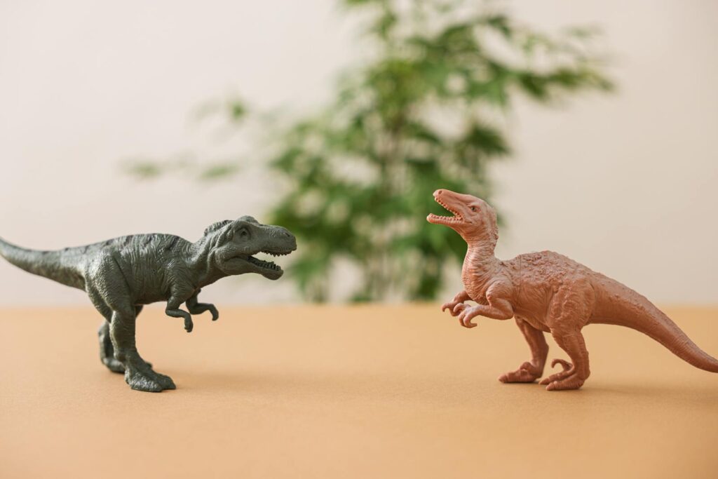 Two toy dinosaur figures set against a natural background on a table.