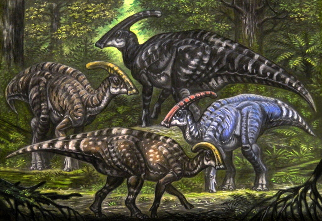 Four dinosaurs with crests on their heads stand in a lush forest. Their varied colors and patterns blend with the greenery, creating a dynamic scene.
