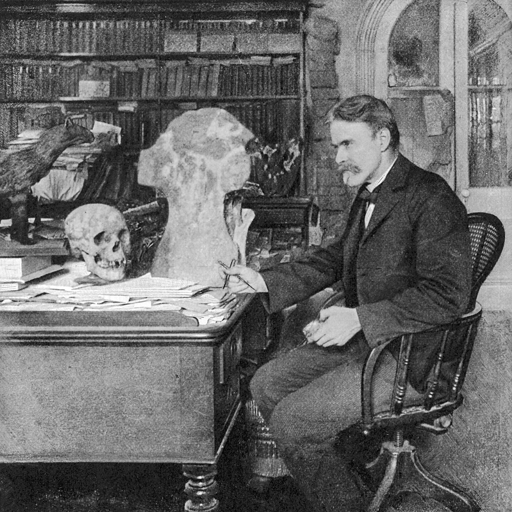 Photo of Edward Drinker Cope in his home office from the 1870s next to a cervical vertebra of Camarasaurus supremus.