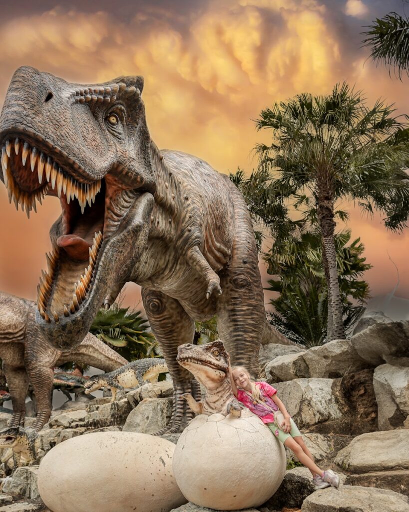 a woman laying on a rock next to a fake dinosaur