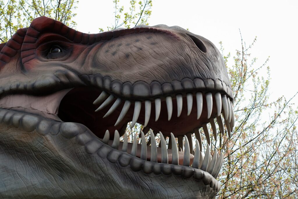 A close up of a dinosaur's mouth with trees in the background