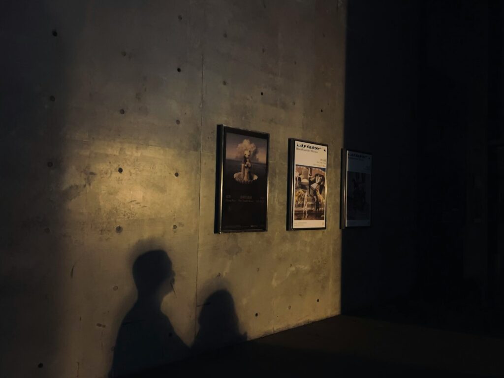a person standing next to a wall with posters on it