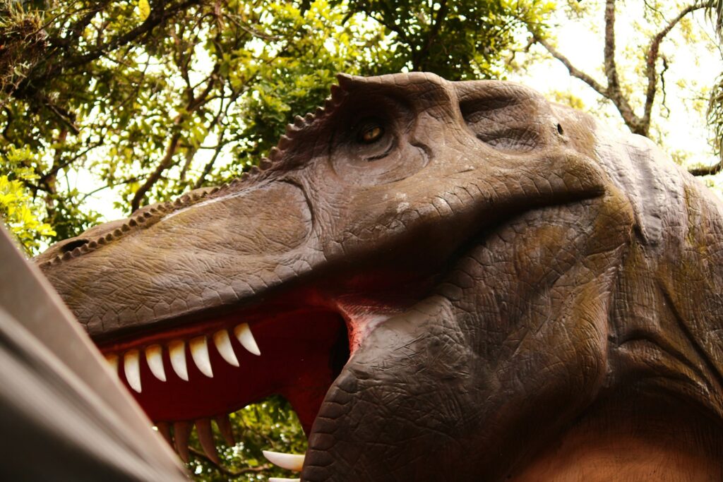 A close up of a dinosaur head with trees in the background