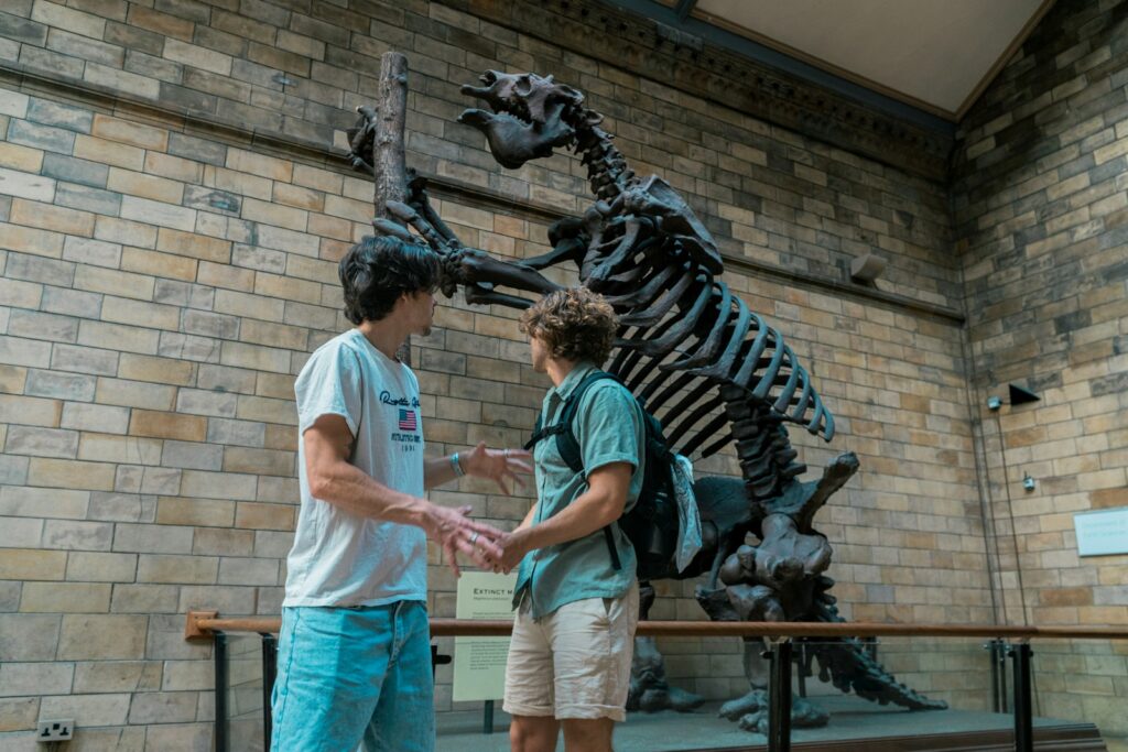 Two boys standing in front of a dinosaur skeleton