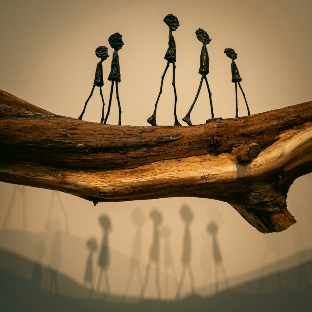 Sculptures of people walk across a log.