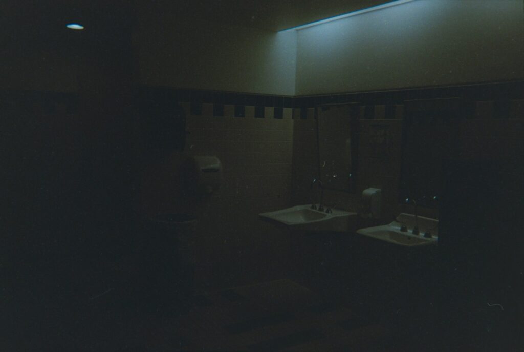 A dark and dim bathroom with sink and mirror.