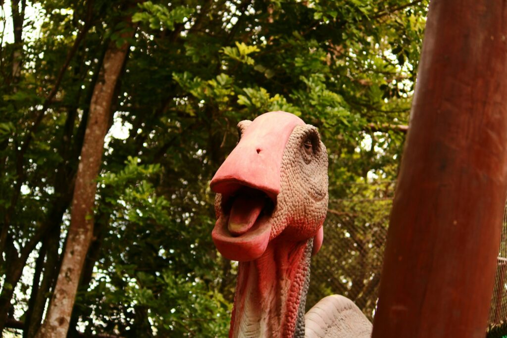 A fake dinosaur head sticking out of a wooden pole