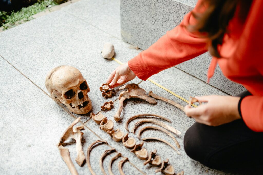 a woman kneeling down next to a human skeleton